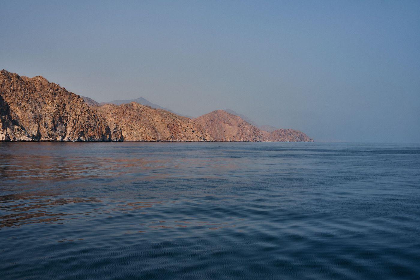 Arid coastline meeting calm turquoise water under a clear sky