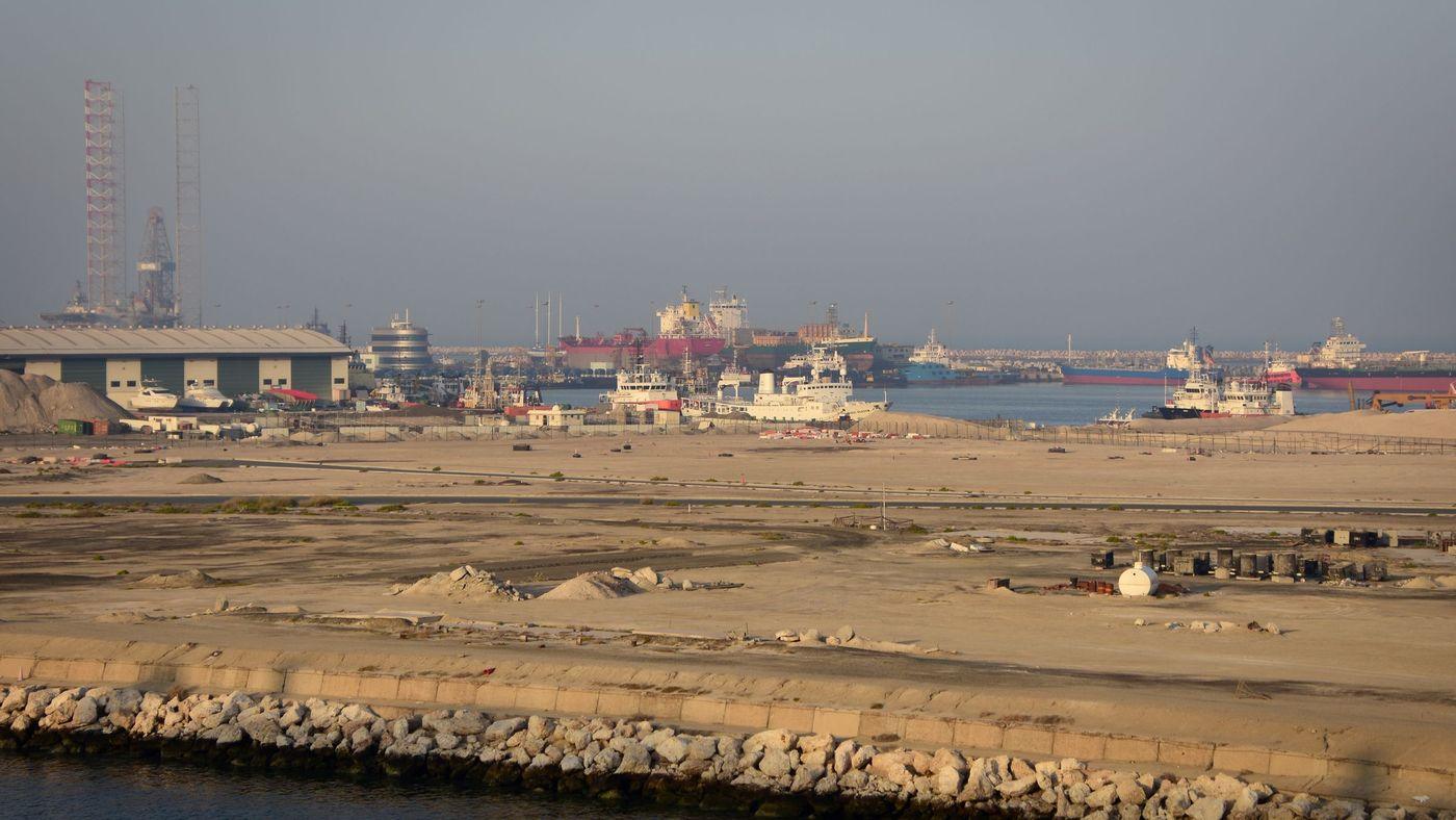 A commercial port at dusk with tankers and support vessels moored along the waterfront